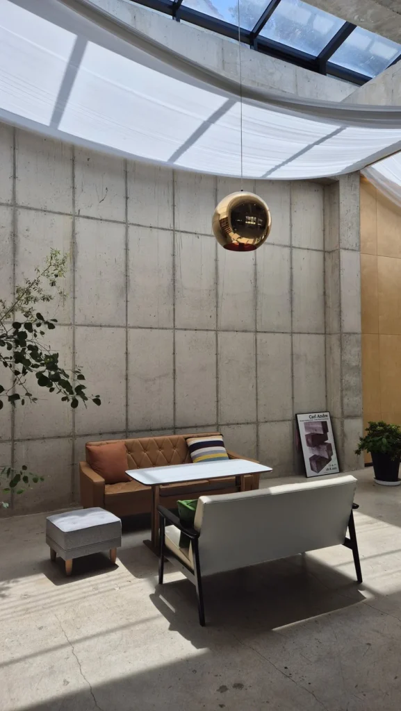 Soaring raw-concrete atrium with a copper pendant lamp at La Montagna cafe